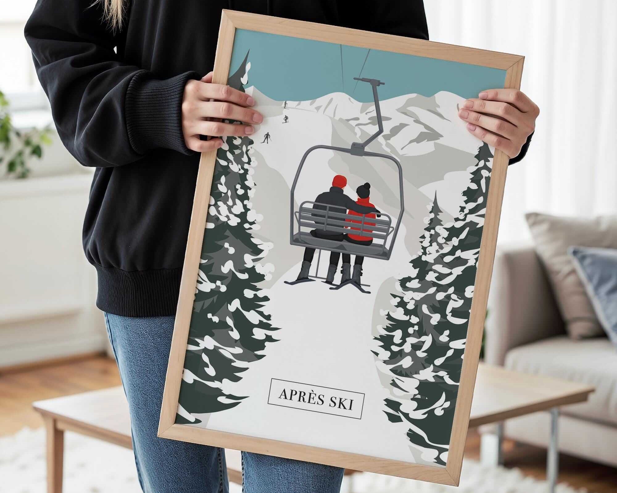 A person is holding a framed picture of a ski lift with two people on it, in a snowy mountain setting.