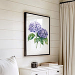 a white dresser with a framed picture of purple hydrangeas hanging on the wall above it.