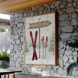 a picture of a ski lodge hangs on a stone wall