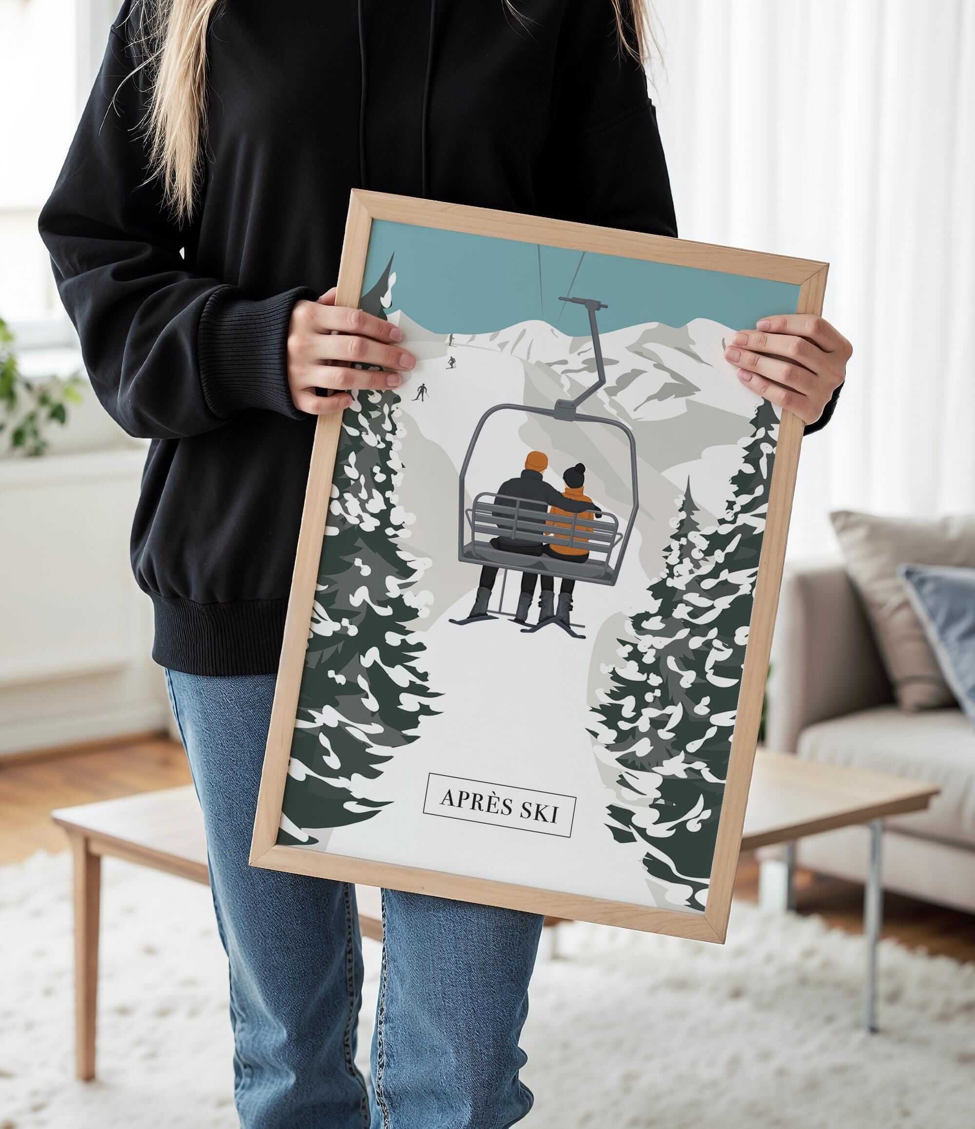 A person is holding a framed picture of a ski lift with two people on it, in a snowy mountain setting.