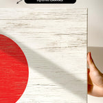 a hand holding a piece of wood with a red circle on it