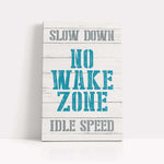 a wooden sign that says slow down no wake zone