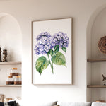 a framed painting of purple hydrangeas hanging on a wall in a living room.