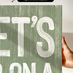a person holding up a green sign with white letters
