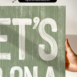 a person holding up a green sign with white letters