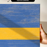 a hand holding a piece of wood with a yellow and blue stripe