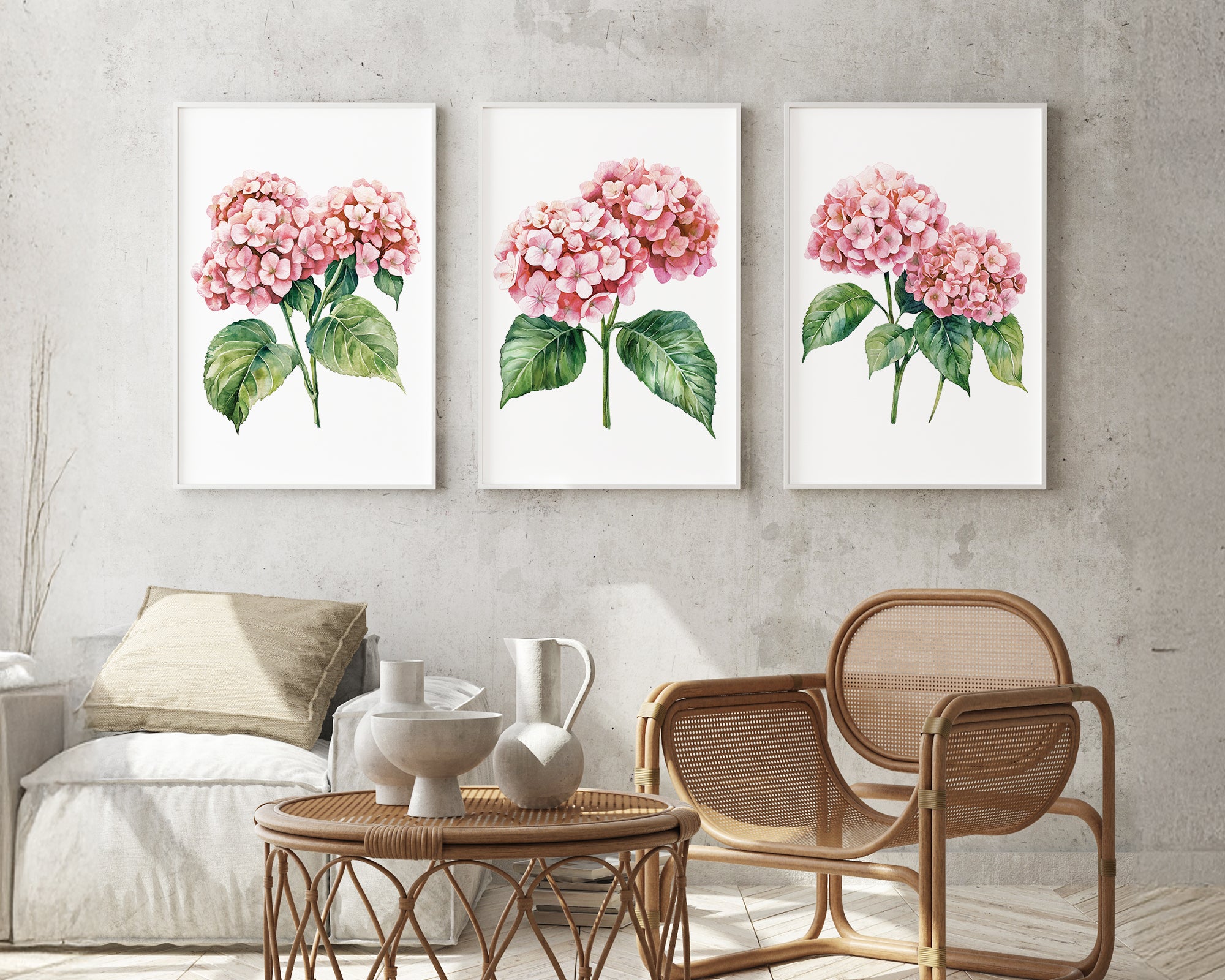 a cozy living room with a wicker coffee table, a wooden chair, and three framed watercolor paintings of pink hydrangeas hanging on the wall above the seating area.