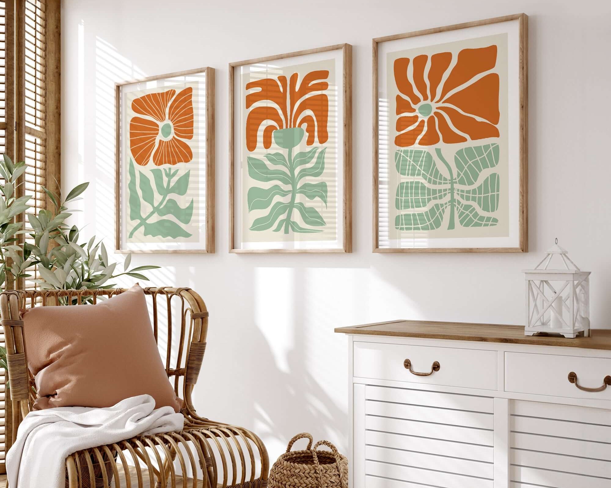 A rattan chair and white cabinet accent a room adorned with the Flower Blocks Triptych | Set of Three Prints | 012, perfect framed abstract floral wall art for stylish home decor.