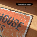 a close-up of a worn, orange-colored sign with the word "HOUSE" written on it.