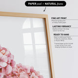 a framed print of pink flowers, with a natural frame.