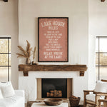 a cozy living room with a rustic fireplace, a wooden mantel, and a framed sign that reads "LAKESHORE RULES" in a vintage style.