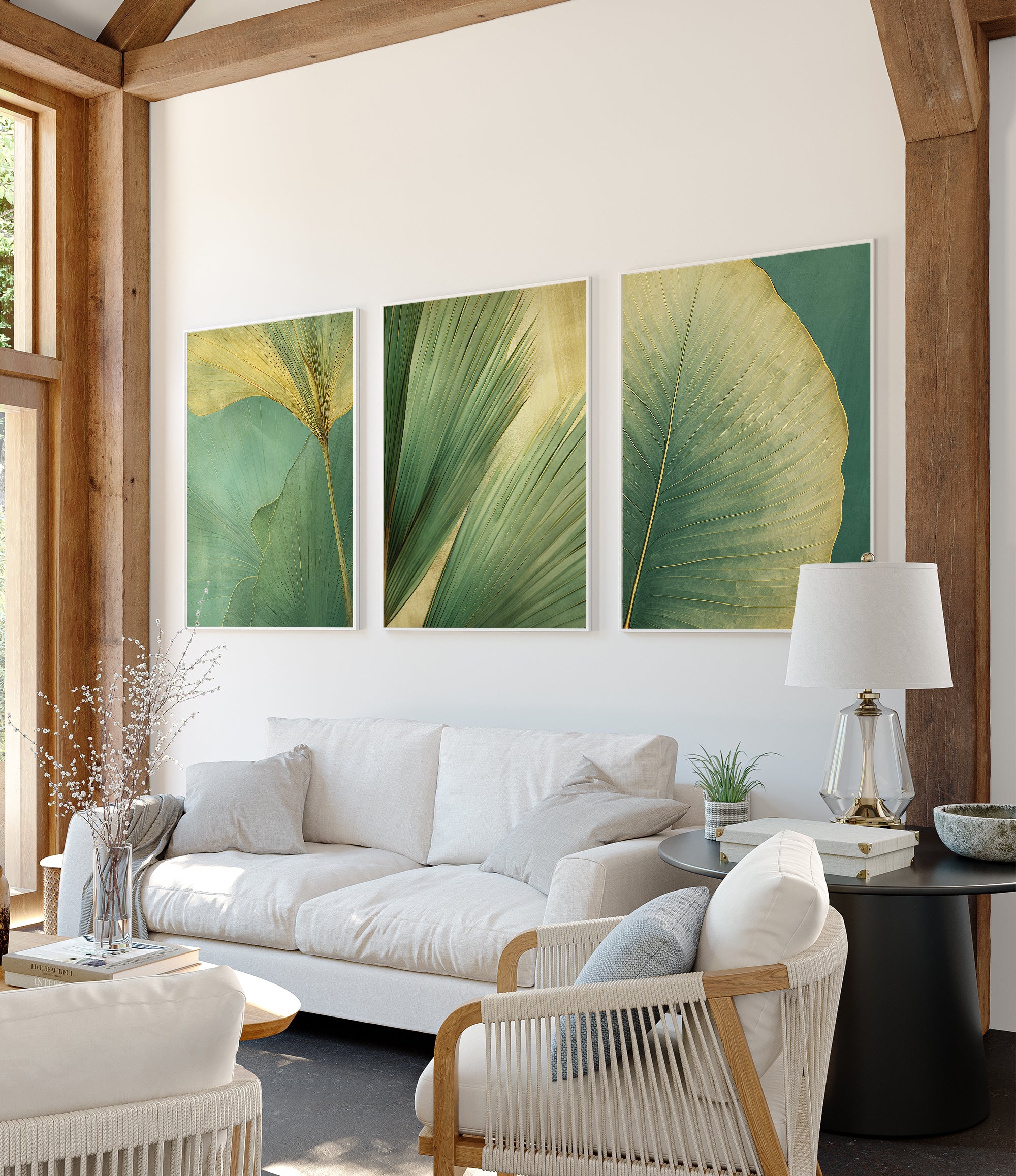 a modern living room with a white sofa, a black coffee table, and three framed prints of green leaves on the wall.