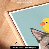 a close-up view of a framed artwork depicting a cat and a yellow duck. The artwork is framed in a natural frame, and the text indicates that the artwork wraps around the sides of the canvas, and all canvas prints include hanging hardware and high-quality archival inks.