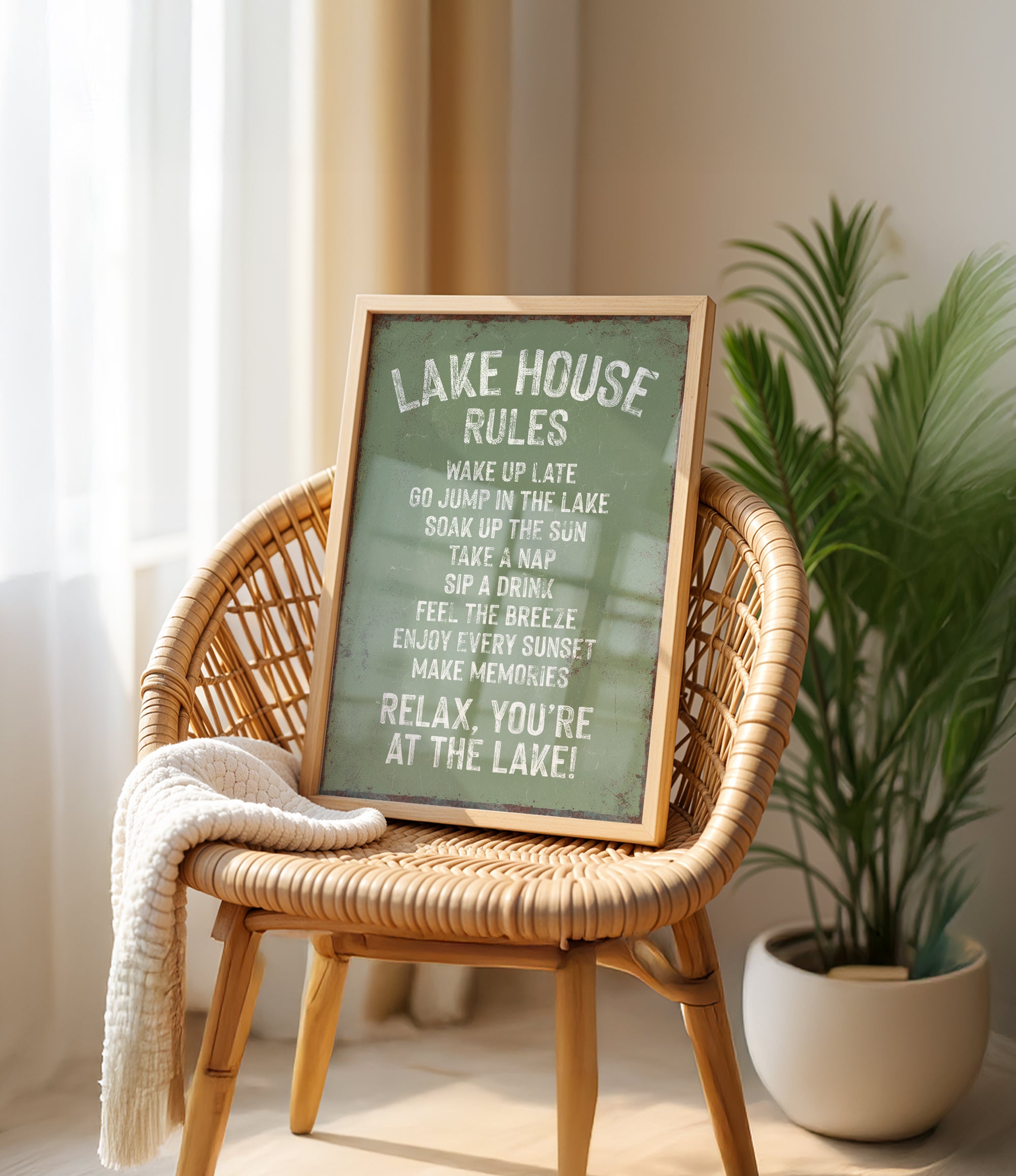 A framed sign on a wicker chair, displaying the rules of a lake house, with a potted plant in the background.