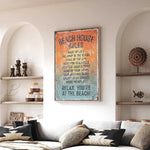 a living room with a large framed sign that reads "BEACH HOUSE RULES" hanging on the wall. The sign lists various beach-related rules, such as "Make up at the beach", "JUMP IN THE OCEAN", and "KEEP THE SEASHELLS HANDLEED OUTSIDE". The room also includes a couch, decorative items, and shelves, creating a cozy and beach-themed atmosphere.