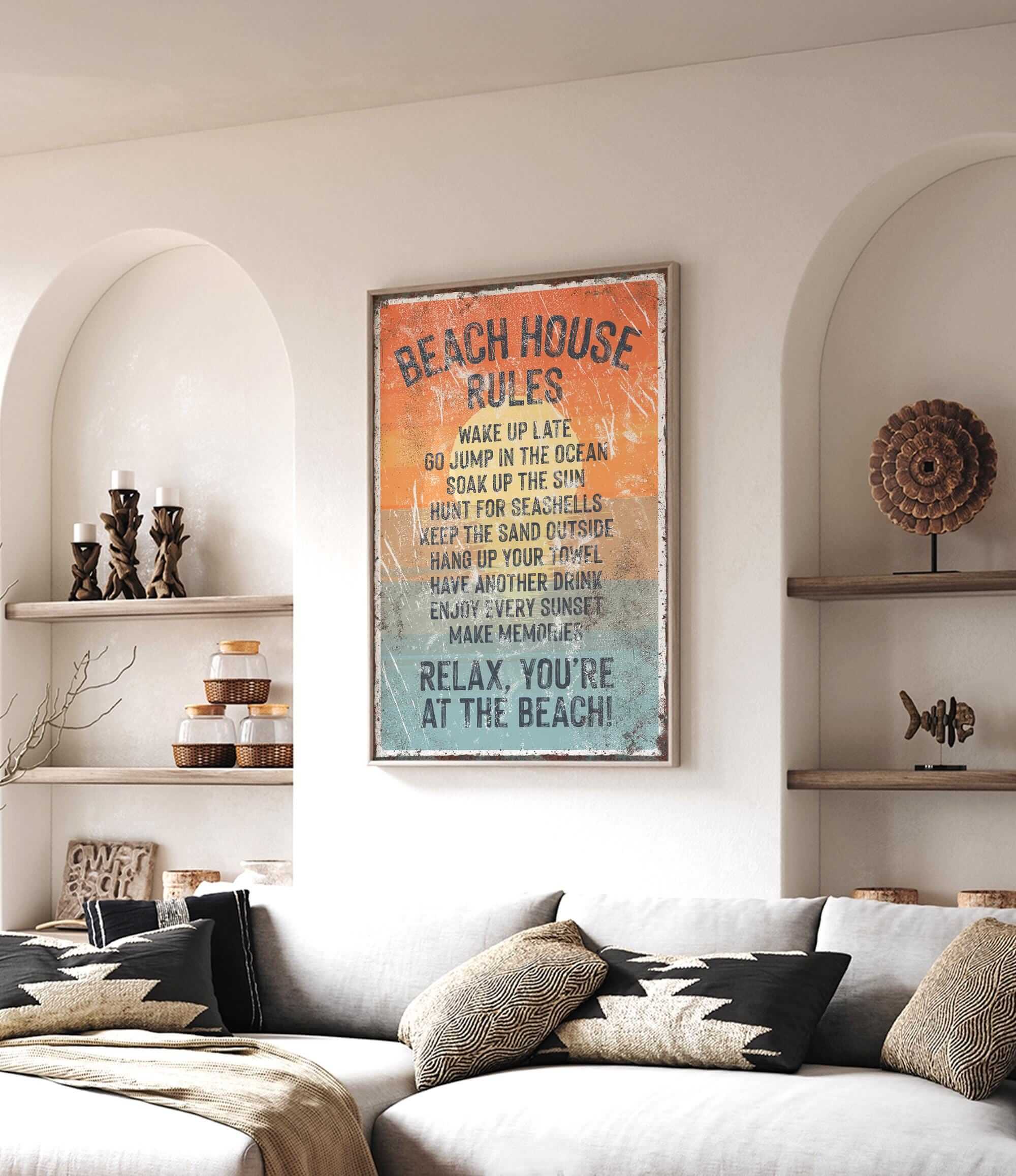 a living room with a large framed sign that reads "BEACH HOUSE RULES" hanging on the wall. The sign lists various beach-related rules, such as "Make up at the beach", "JUMP IN THE OCEAN", and "KEEP THE SEASHELLS HANDLEED OUTSIDE". The room also includes a couch, decorative items, and shelves, creating a cozy and beach-themed atmosphere.