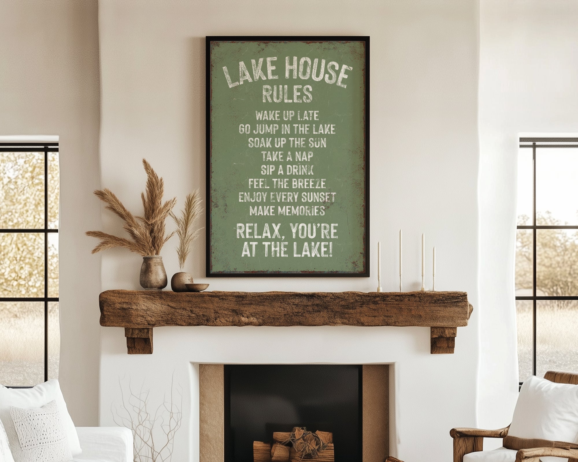 a cozy living room with a fireplace, a wooden mantel, and a framed sign that reads "Lake House Rules" above the mantel. The room has a comfortable and inviting atmosphere, with a couch, a chair, and a decorative vase on display.