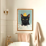 A framed illustration of a black cat with a yellow rubber duck on its head is displayed on the wall above a white bathtub in a bathroom.