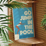 A poster with the text "GO JUMP IN THE POOL" is displayed on a wooden shelf, with a plant visible in the foreground.