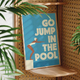 A poster with the text "GO JUMP IN THE POOL" is displayed on a wooden shelf, with a plant visible in the foreground.