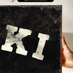 a hand holding a canvas print with a large, distressed letter "K" on it.