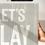 a hand holding a sign that says let&#39;s play