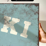 a close-up of a textured blue surface with a large white letter "K" prominently displayed.