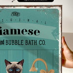 a hand holding a framed print with a cat and a sink, along with some text and graphics.