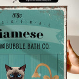 a hand holding a framed print with a cat and a sink, along with some text and graphics.