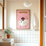 A bathroom with a pink bathtub, a towel, and a plant. Above the bathtub is a framed poster with a dog and the text "Please wash your paws".