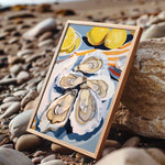 A framed painting of a seashell with a lemon slice on top, placed on a rocky beach.