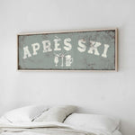 a bed with white pillows and a framed sign above it that says "APRES SKI".