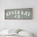 a bed with white pillows and a framed sign above it that says "APRES SKI".