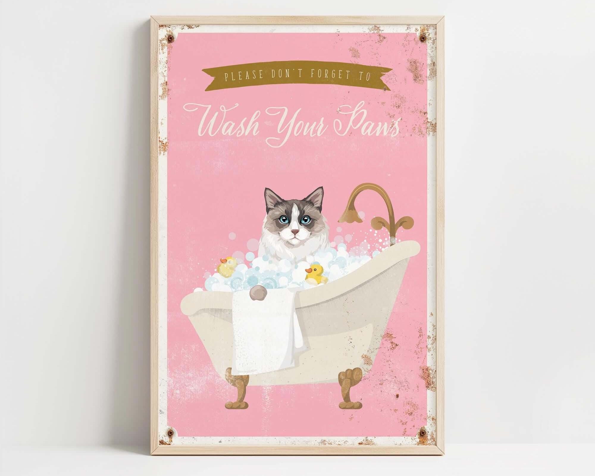A framed poster with a cat sitting in a bathtub filled with bubbles, accompanied by the text "Please don't forget to wash your pans".