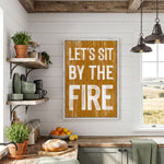 a kitchen with a wooden countertop, shelves, and a framed sign that reads "LET'S SIT BY THE FIRE". The kitchen also has various kitchen items such as a bowl, oranges, and a potted plant.