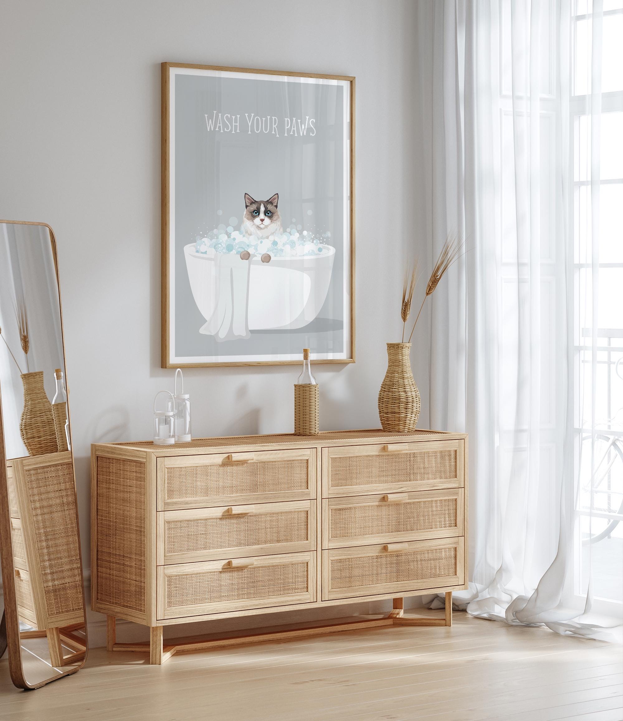 a wooden dresser with drawers, a framed poster of a cat in a bathtub, and a mirror on the wall.