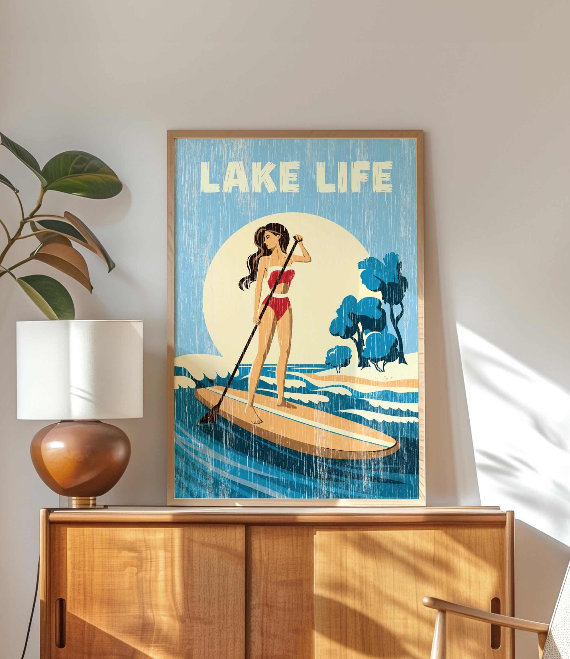 a framed poster of a woman paddleboarding on a lake, with the text "LAKELIFE" prominently displayed.
