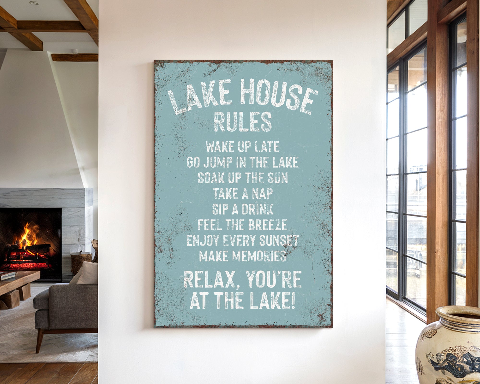 a sign that reads "LAKESHOUSE RULES" hanging on a wall in a room with a fireplace and a vase.