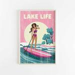 A woman in a pink swimsuit is paddleboarding on a pink surfboard, with a sunset and trees in the background.