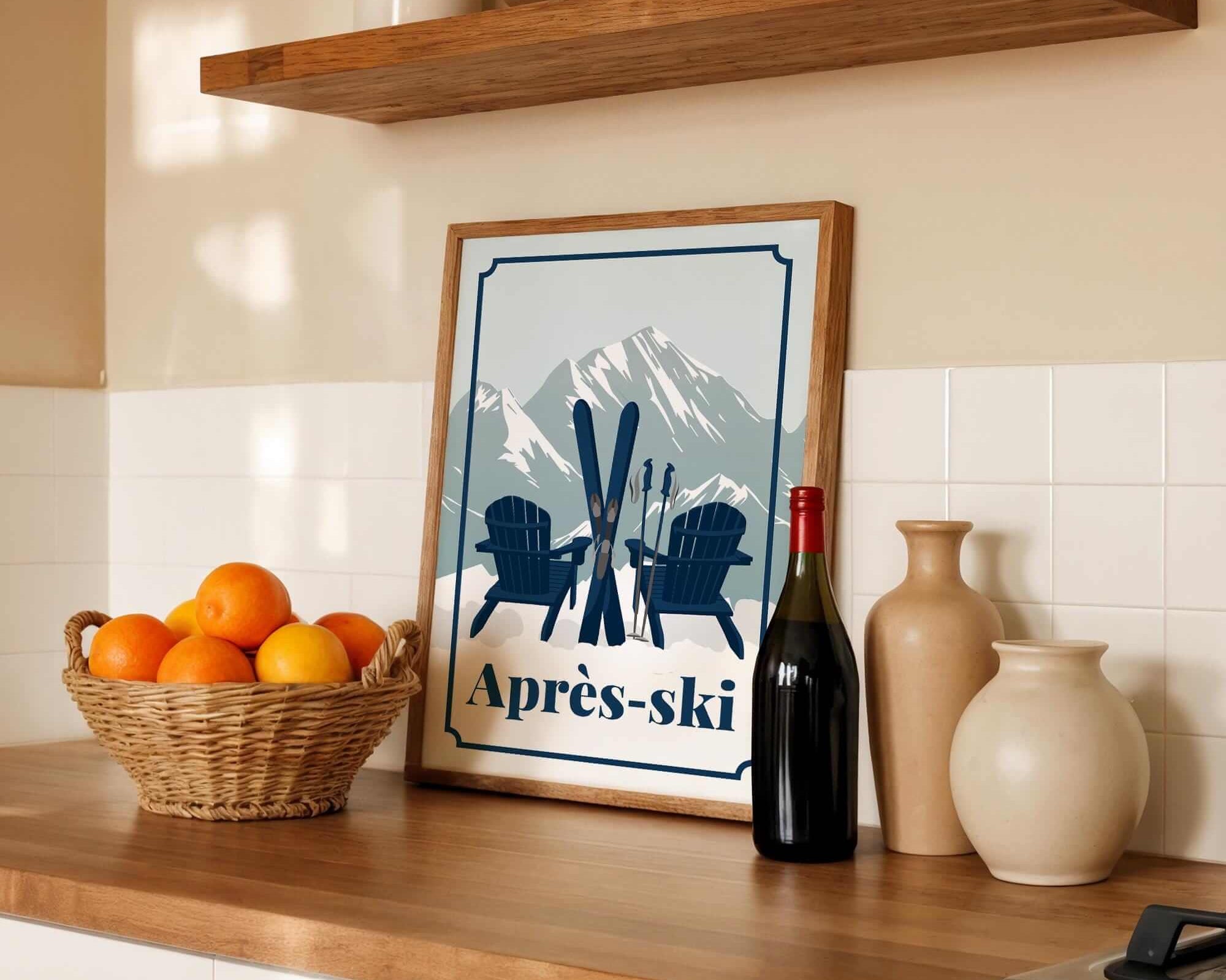 a kitchen counter with a framed poster of a mountain landscape with skis and Adirondack chairs,, a basket of oranges, a bottle of wine, and various decorative items such as vases and a bowl.