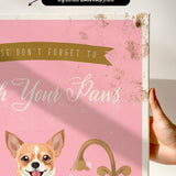 a hand holding a framed print with a pink background and a dog illustration. The text on the print reads "Wash Your Paws".