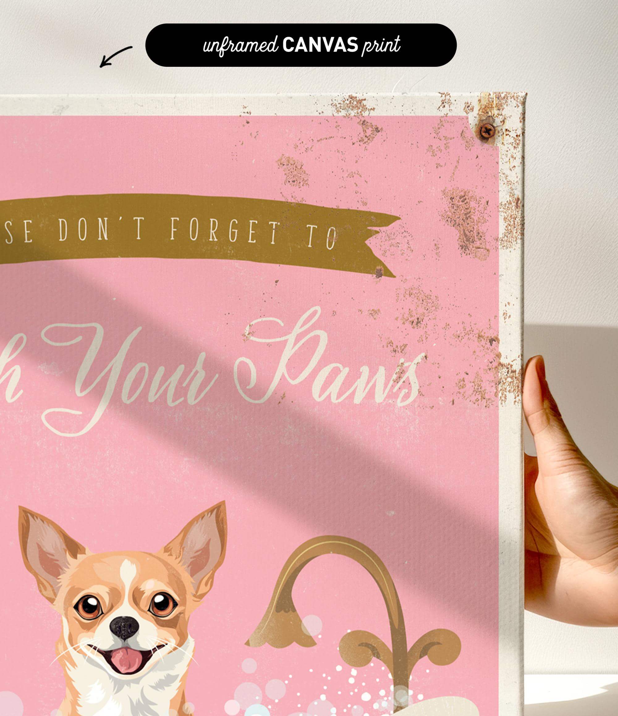 a hand holding a framed print with a pink background and a dog illustration. The text on the print reads "Wash Your Paws".