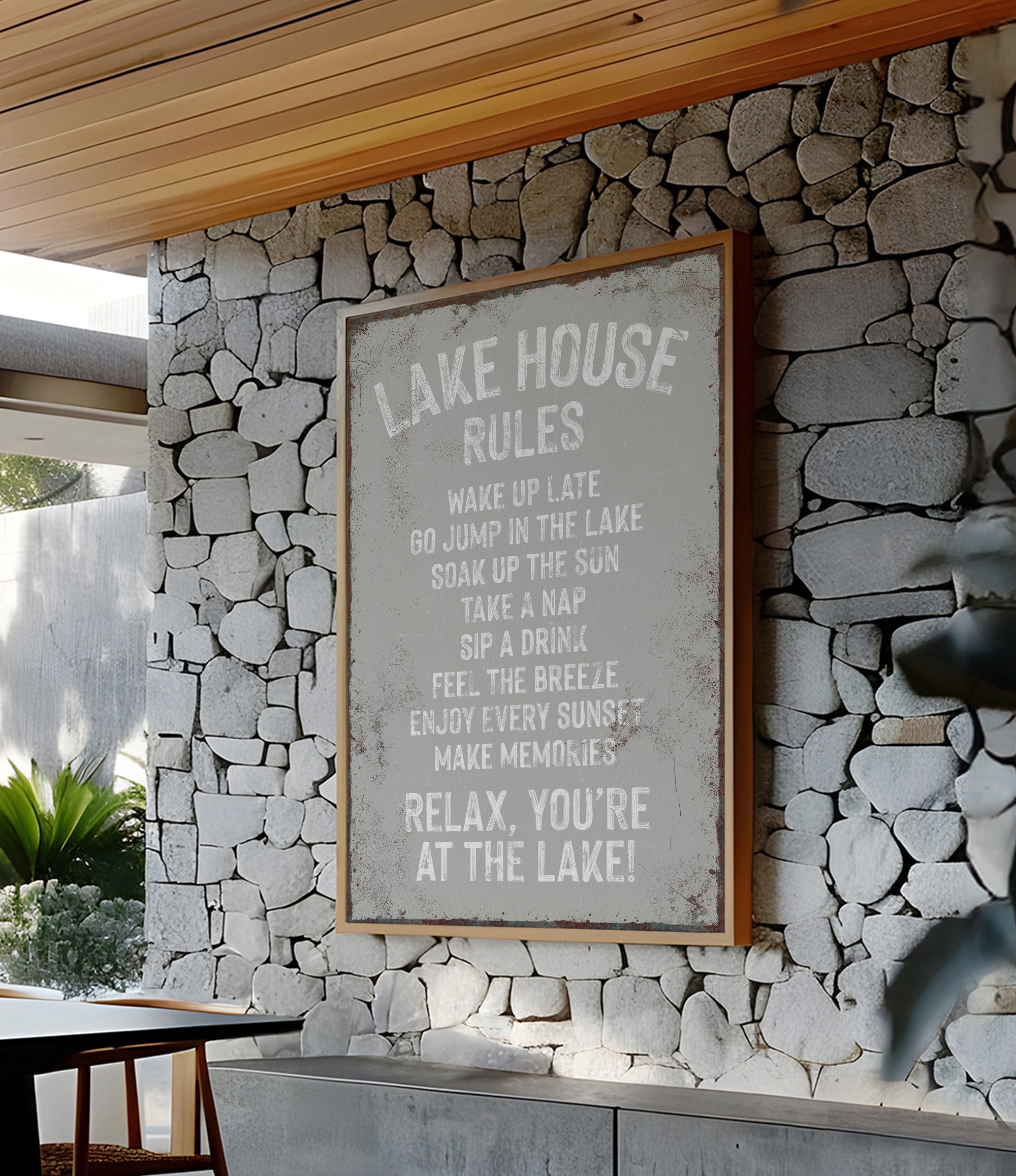 a framed sign with a list of rules for a lake house, mounted on a stone wall.
