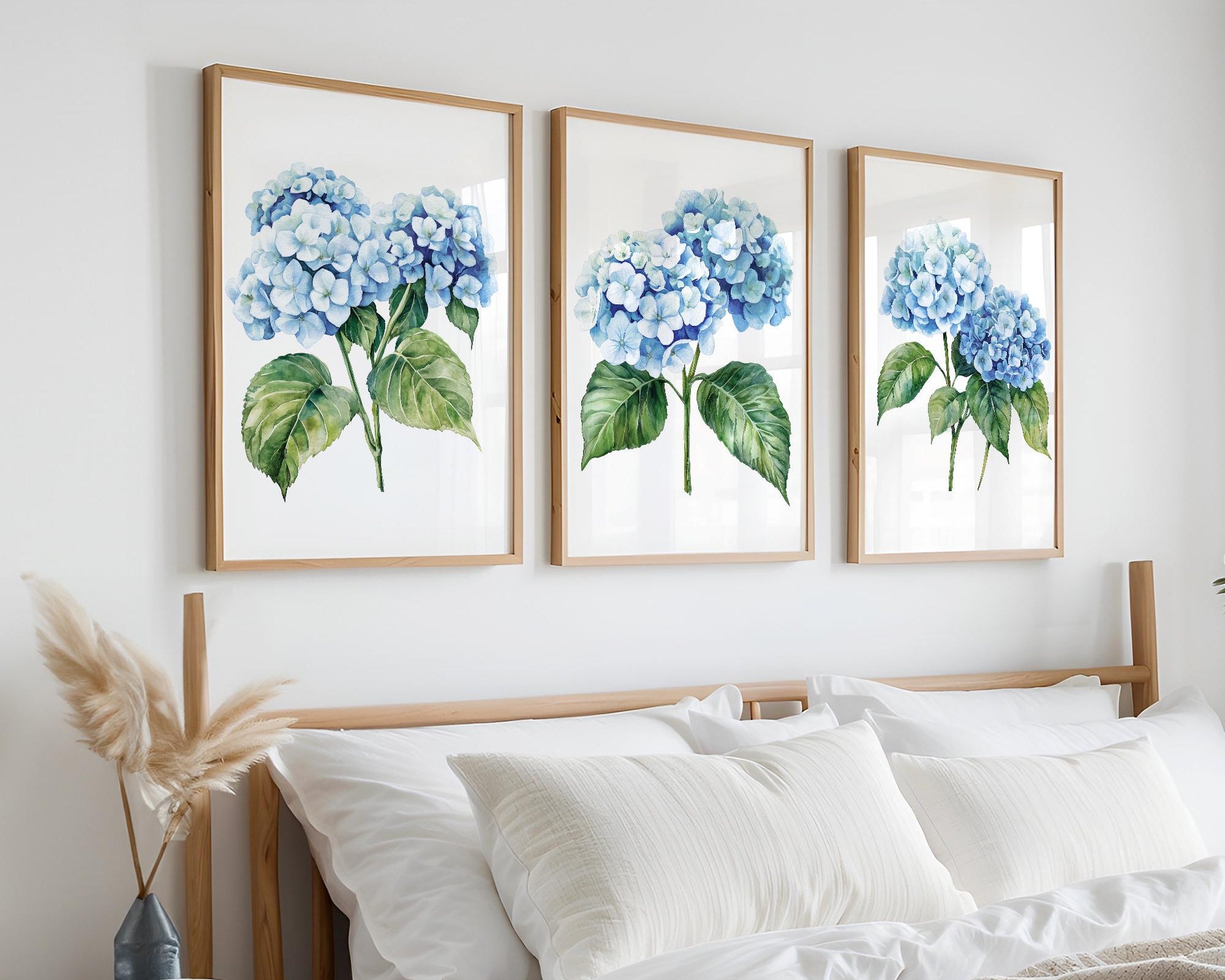 a bedroom with a bed, white pillows, and a framed artwork of blue hydrangeas hanging on the wall above it.