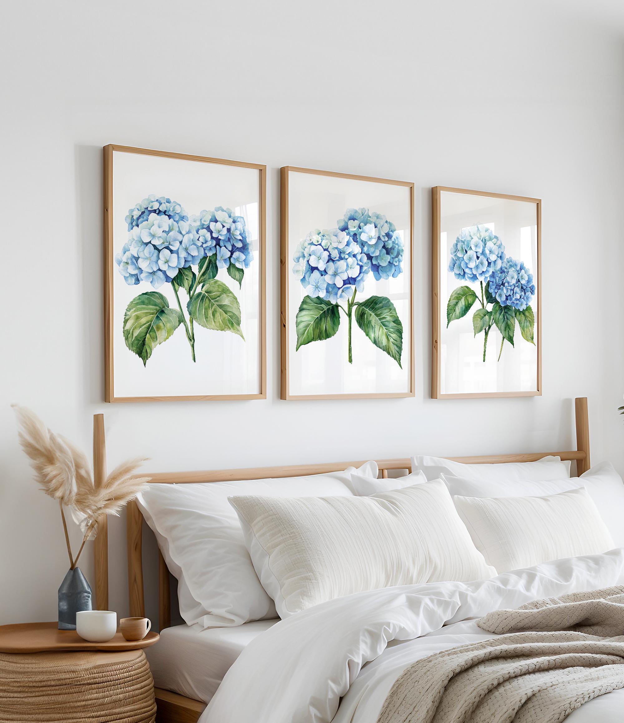 a bedroom with a bed, white pillows, and a framed artwork of blue hydrangeas hanging on the wall above it.