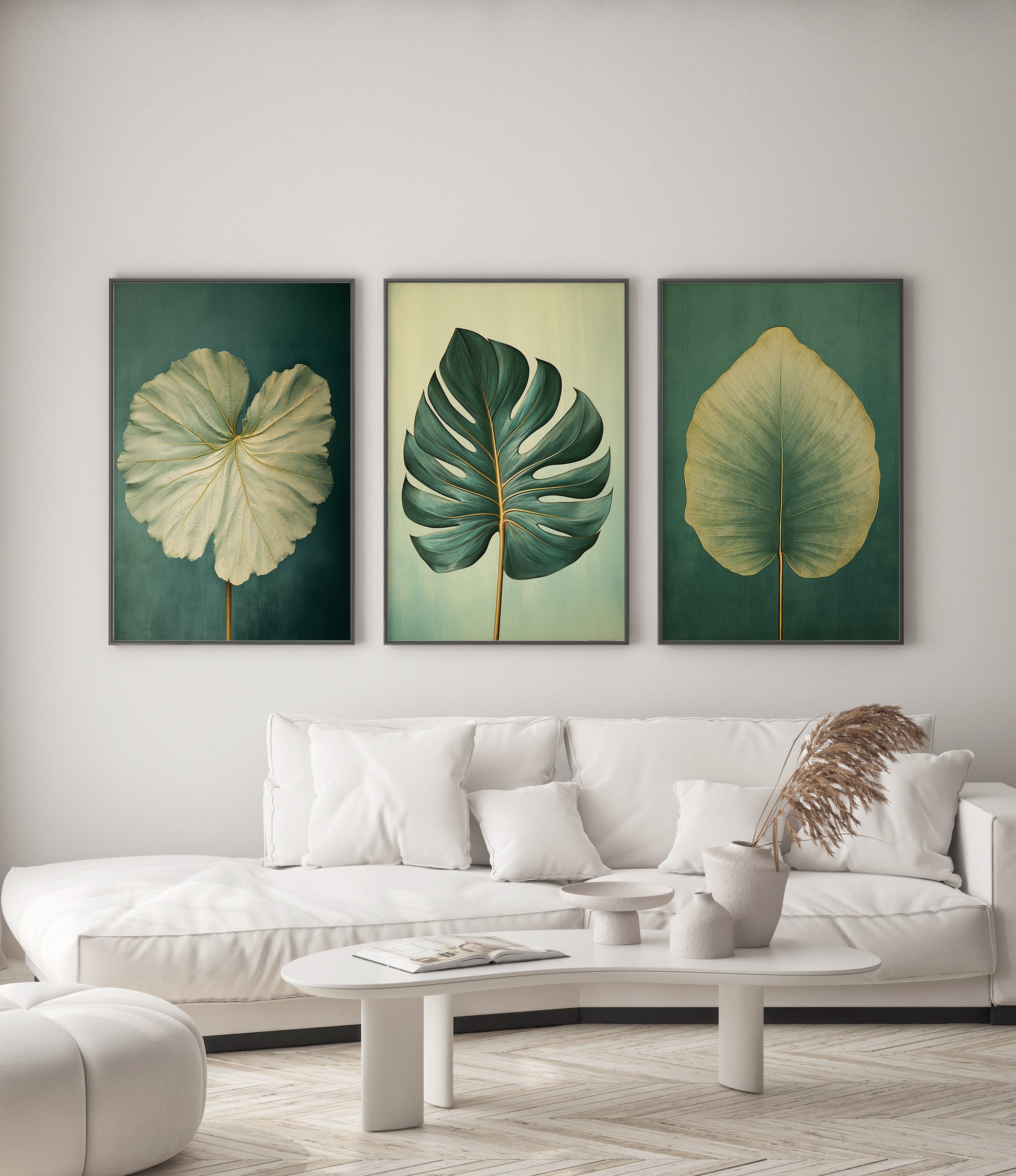 a living room with a white sofa and a coffee table. Above the sofa, there are three framed paintings of tropical leaves in different colors - green, yellow, and white.