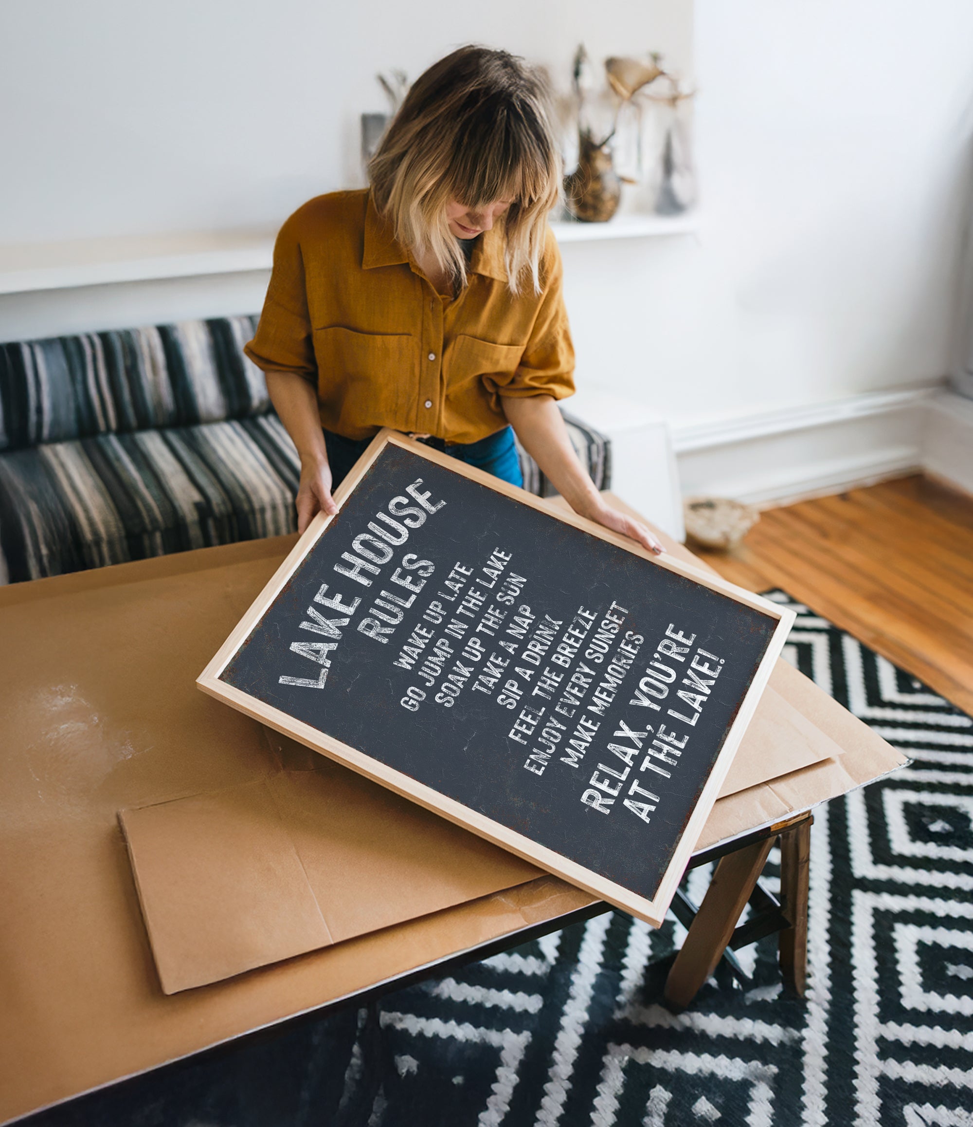A woman in a yellow shirt is holding a black sign with white text, which appears to be a message or notice.