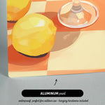 The image is an aluminum print depicting a still life of a lemon and a wine glass on a checkered tablecloth.