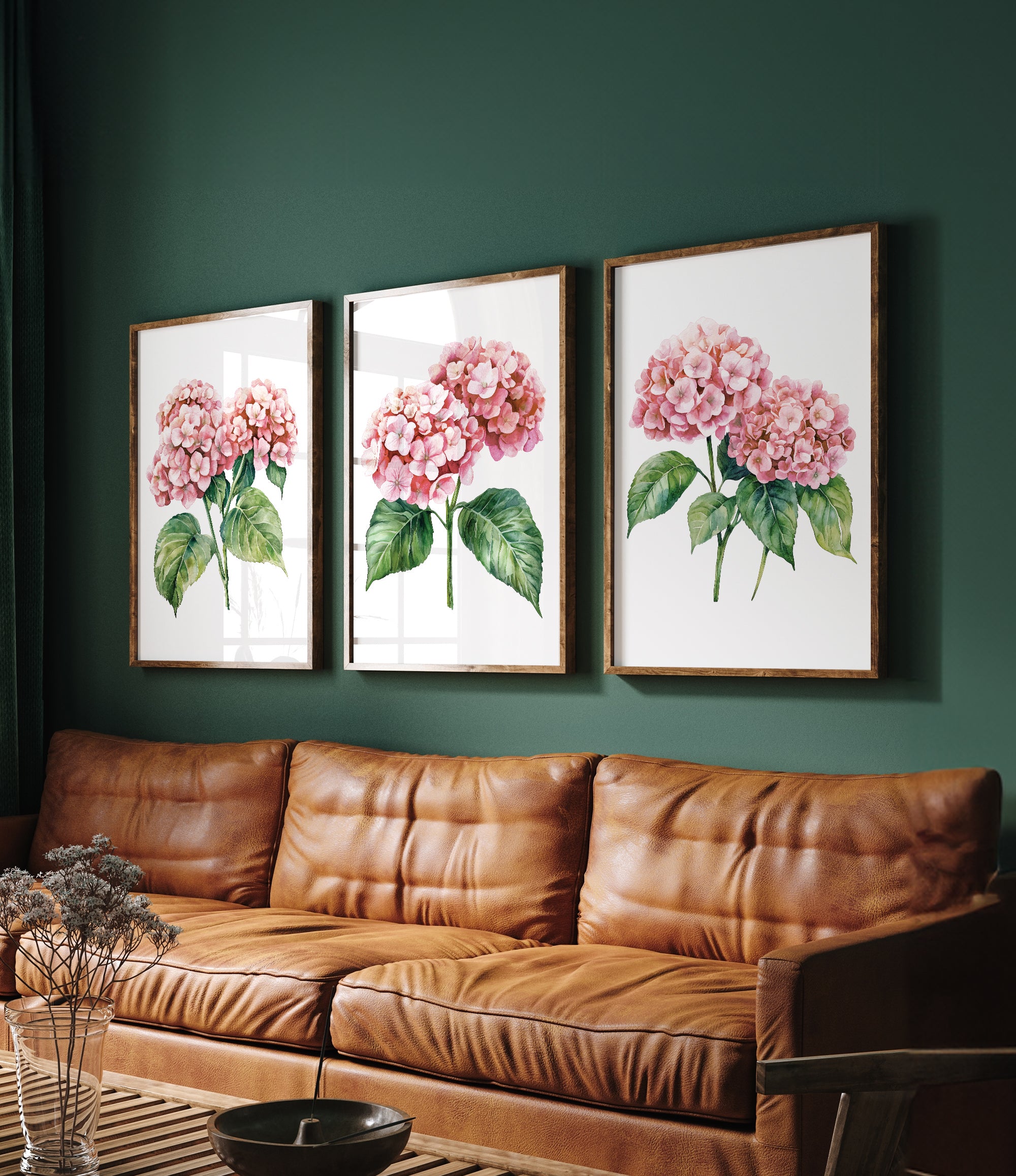 a cozy living room with a brown leather couch and three framed watercolor paintings of pink hydrangeas hanging on the wall above it.
