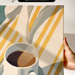 a hand holding a white mug filled with coffee, set against a background of yellow and white striped fabric.